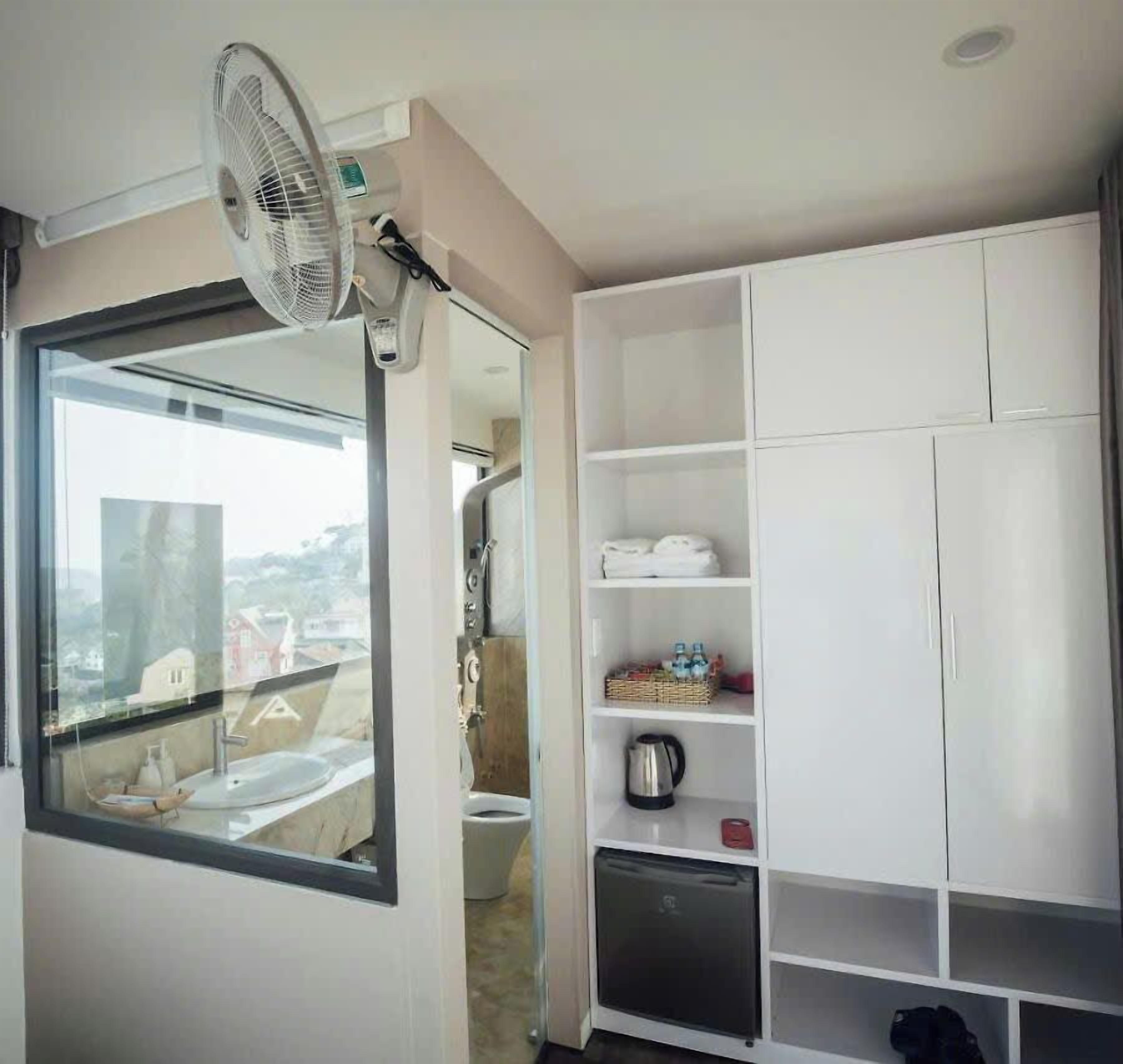 A compact room with a large window, a white wardrobe, and a small kitchenette area.