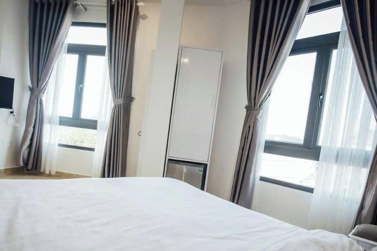 A hotel room with a large bed, a wardrobe, and curtains on the windows.