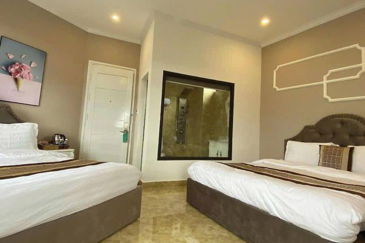 A hotel room with two beds, a bathroom mirror, and a door.