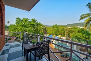 A balcony with a checkered floor, two chairs, a table, and a potted plant. - Hotel Vaggi's Place (Arpora)