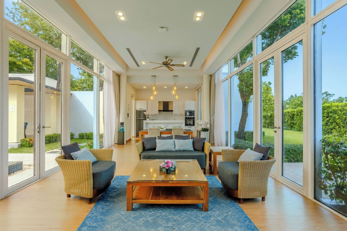 A spacious living area with a sofa set, a coffee table, and large windows offering a view of the outdoors.