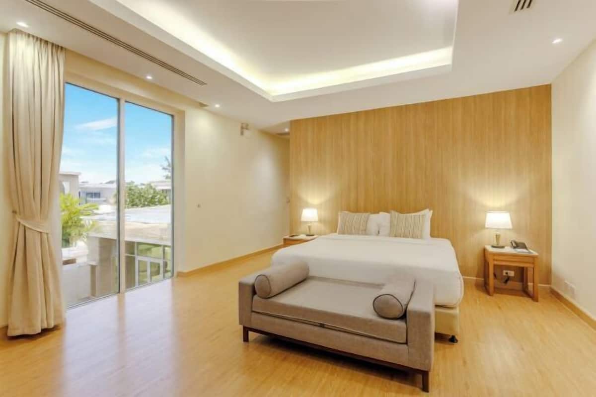 A hotel room with a bed, bedside tables, a sofa, and a sliding glass door to the outside.