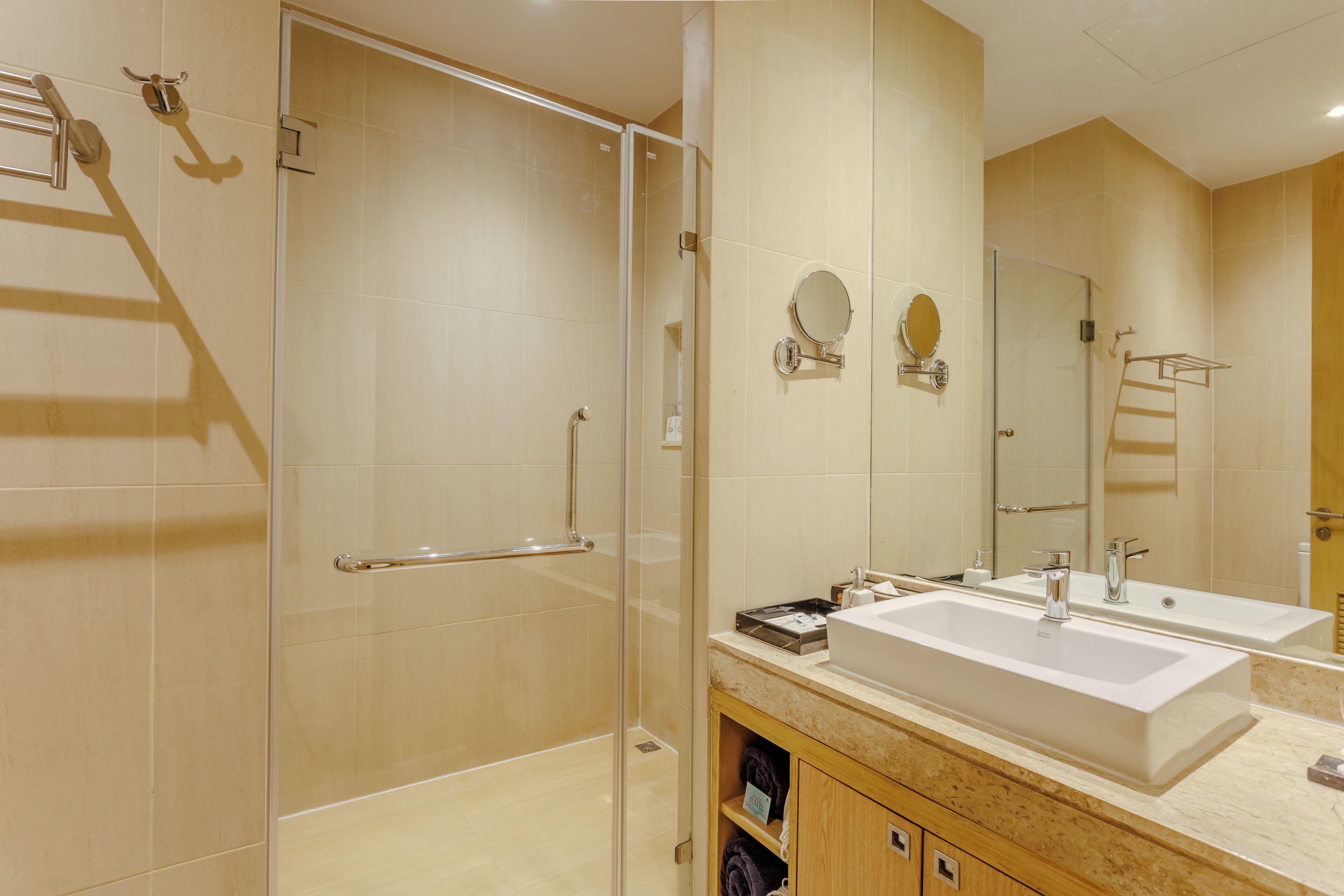 Een moderne badkamer met een douchecabine van glas, een dubbele wastafel en een grote spiegel.