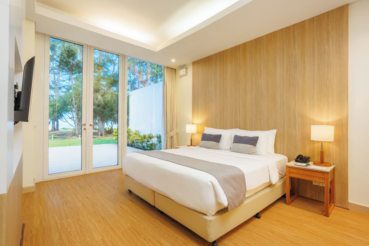 A modern hotel room with a large bed, bedside lamps, a wooden nightstand, and a TV.