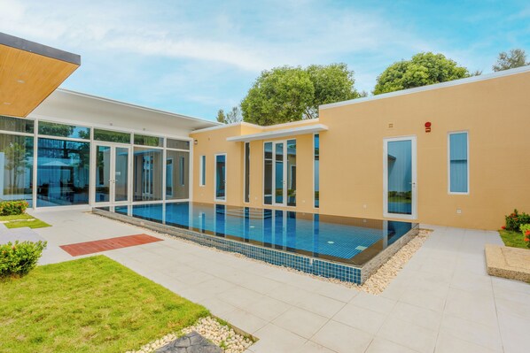 Un bâtiment moderne doté d’une piscine, de portes vitrées et d’un jardin bien entretenu.