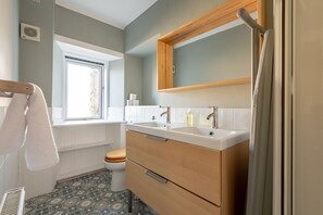 A bathroom with a window, two sinks, a toilet, and patterned floor tiles. - Market Street (No 97) (St Andrews)