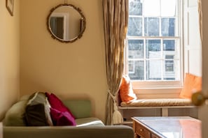 A room with a window seat, a mirror, and a small table. - Market Street (No 97) (St Andrews)