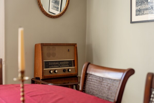 A room with a wooden radio, a mirror, and a framed picture on the wall.