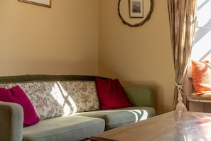 Un salon avec un canapé, une table et un tableau encadré au mur.
