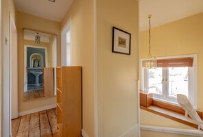 Ein Flur mit Holzboden, einem weißen Waschbecken und einem gerahmten Bild an der Wand.