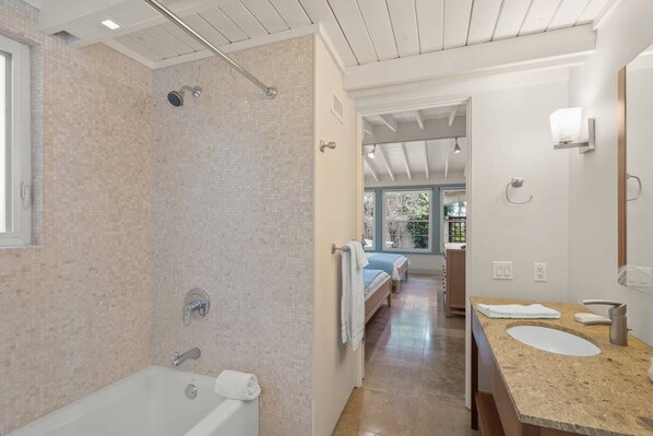 A modern bathroom with a large bathtub, a shower area, and a vanity with a sink and mirror.