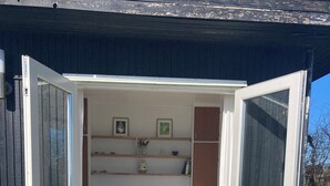 Une petite chambre à coucher ouverte, comprenant un lit, une table de chevet et une étagère avec des objets décoratifs.