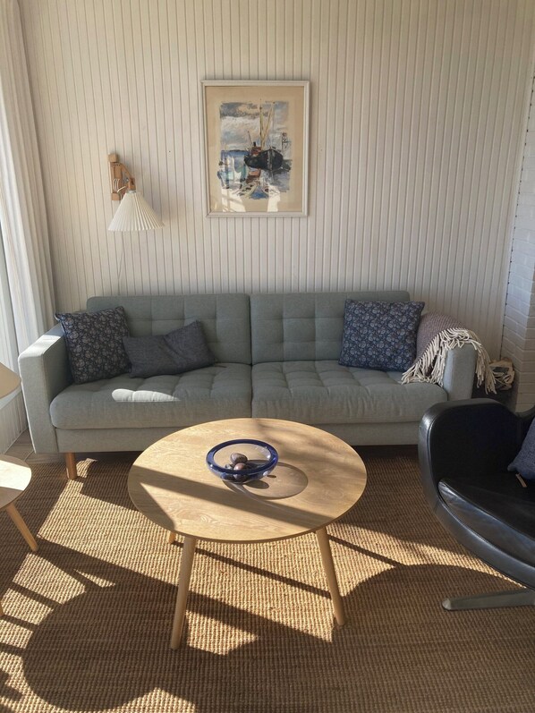 A living room with a sofa, a coffee table, a lamp, and a framed picture on the wall. - Holiday home by the water in Rødvig, Stevns (Rødvig Stevns)