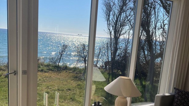 Une pièce dotée de grandes fenêtres, d’une lampe, d’un canapé et offrant une vue sur la mer.