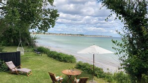Une terrasse avec une table et des chaises, un fauteuil suspendu et une vue sur la plage.