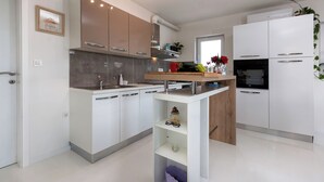 A modern kitchen with white cabinetry, a built-in oven, and a small island with a sink.