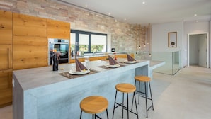 A modern kitchen with a large island, wooden cabinets, and a stone backsplash.