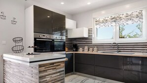 Una cocina moderna con una isla central, hornos integrados y un ventanal con vistas.