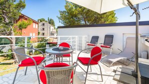 An outdoor patio with wicker chairs and red cushions, a white umbrella, and a grill area. - Villa Ziziphus - Private Pool with Jacuzzi (Premantura)