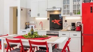 A modern kitchen with white cabinets, a red refrigerator, and a dining area with red chairs and a table set with a red placemat. - Villa Ziziphus - Private Pool with Jacuzzi (Premantura)