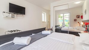 A hotel room with a bed, a TV mounted on the wall, a bedside table with a lamp, and a large mirror reflecting the room. - Villa Ziziphus - Private Pool with Jacuzzi (Premantura)