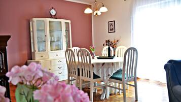 A dining area with a white table, four chairs, a white cabinet, and a clock on the wall.