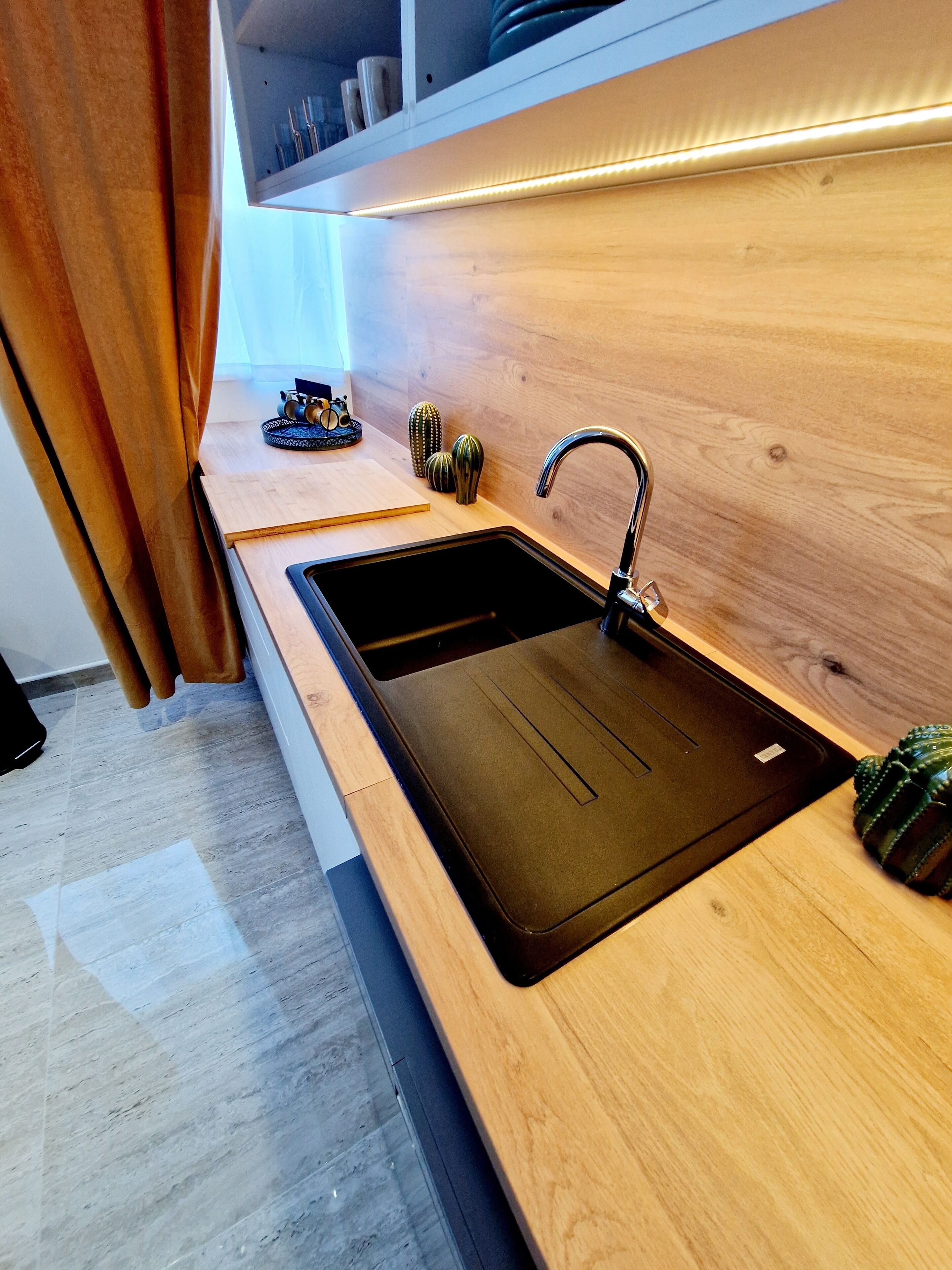 Une cuisine moderne avec un évier noir, un plan de travail en bois et un robinet en acier inoxydable.
