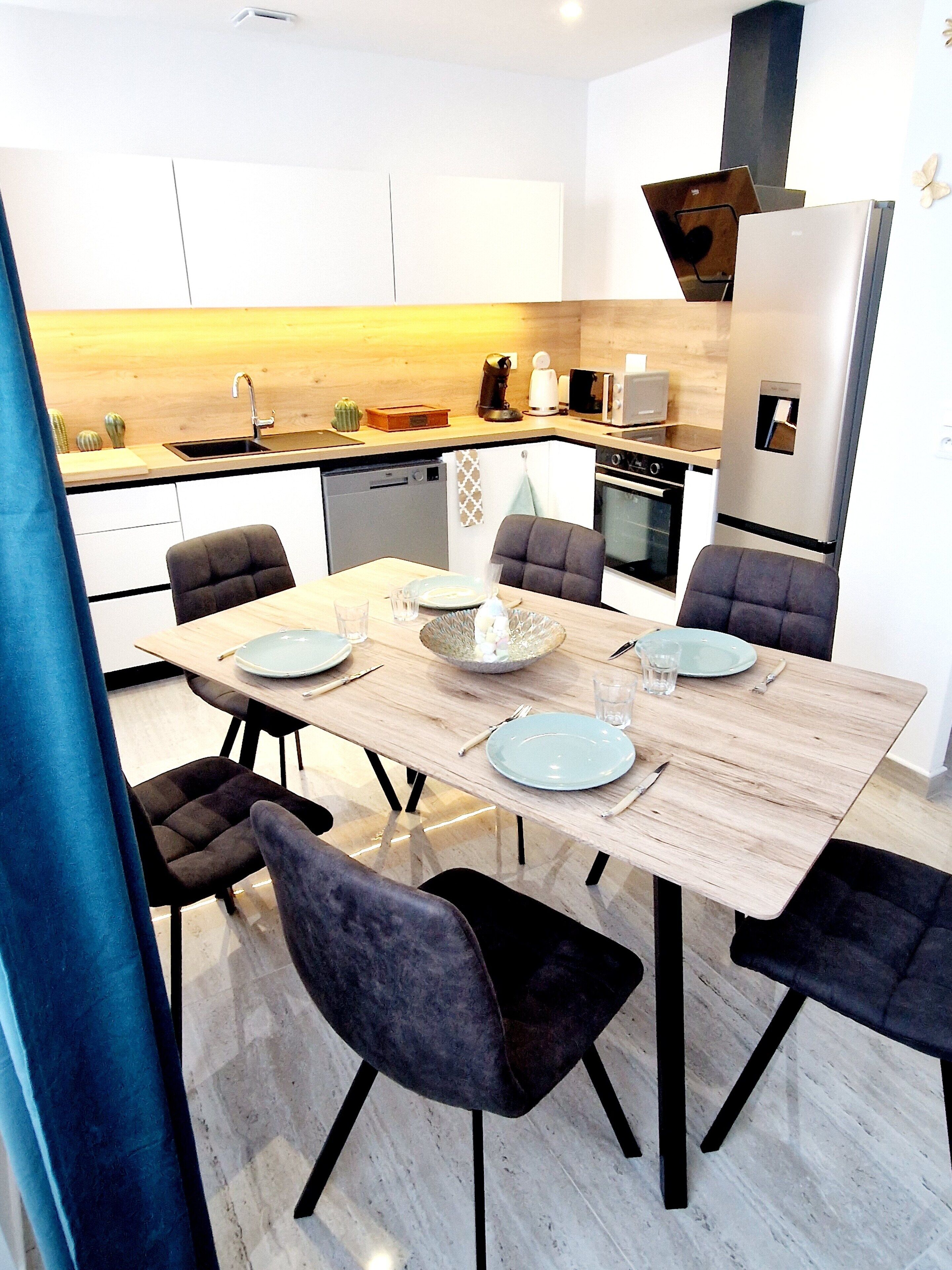 Eine moderne Küche mit Essbereich, ausgestattet mit einem Holztisch, dunklen Stühlen und einem eingebauten Ofen.