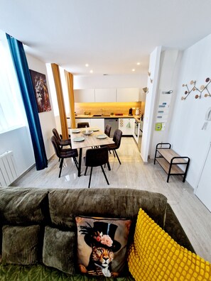Cozy living space with a dining area and kitchenette, featuring a sofa, dining table, and oven.