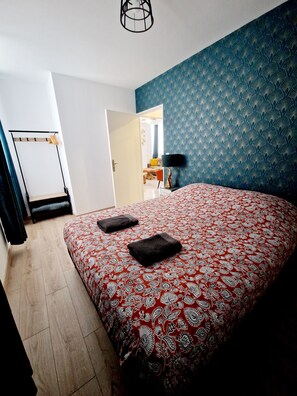 Relax in a spacious room with a large bed, blue patterned wallpaper, and a wooden bench.