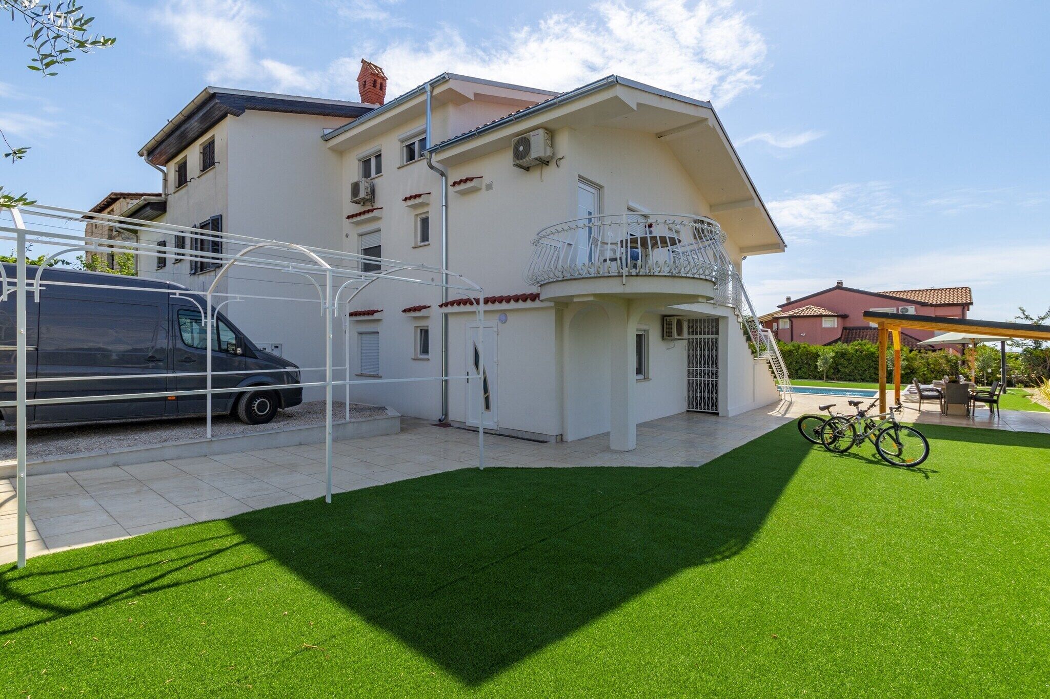 Une maison moderne à deux étages, dotée d’un balcon, d’une terrasse couverte et d’un vélo.