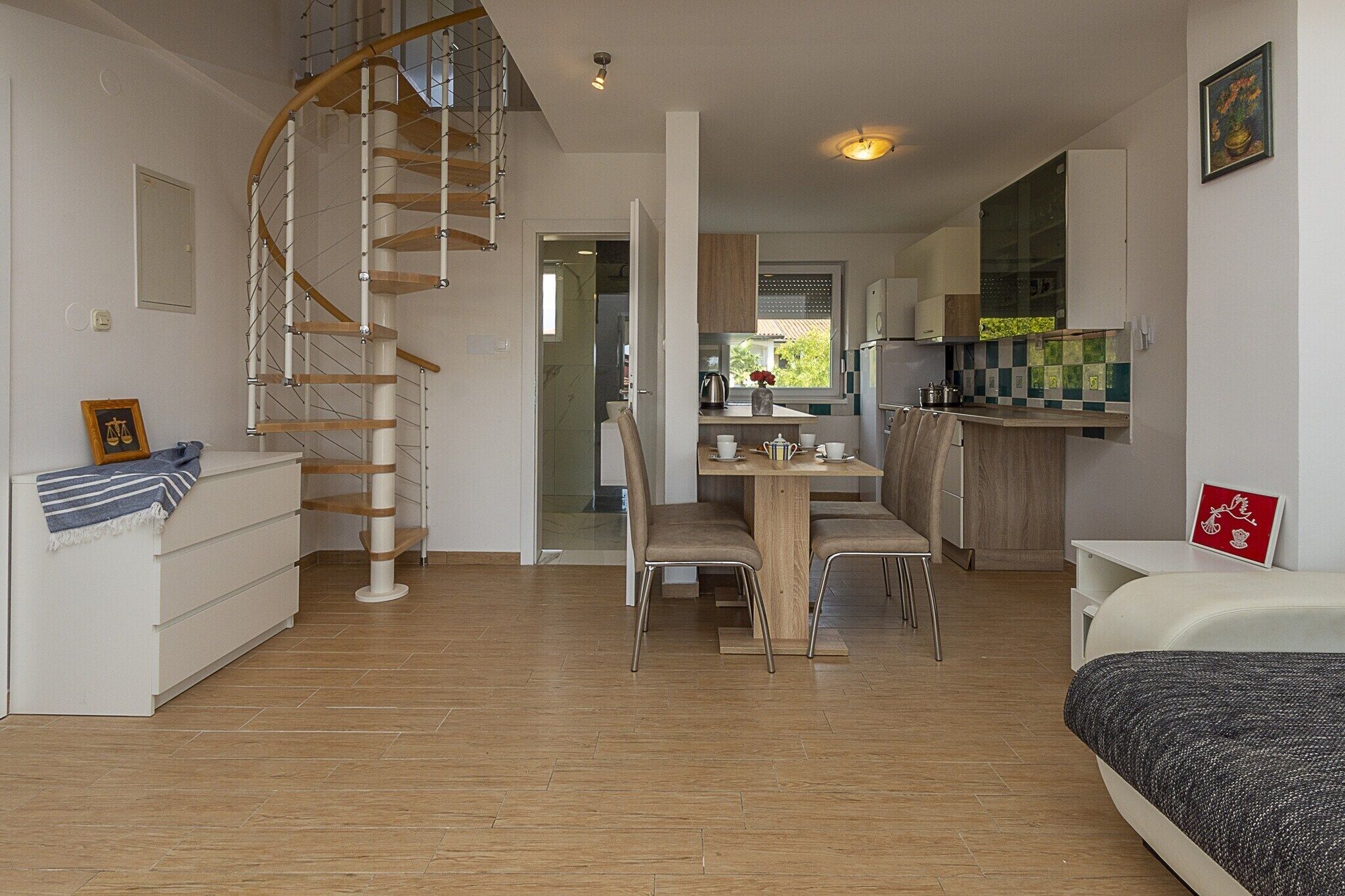Um apartamento moderno com escada em caracol, área de jantar e cozinha.