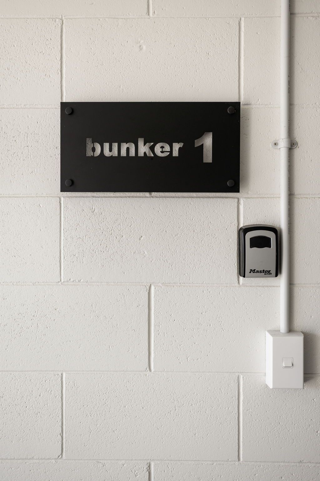 A wall-mounted sign with the text 'bunker 1' and a Master Lock padlock.