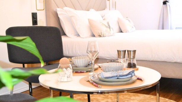 Un coin repas aménagé avec soin, avec une table dressée pour deux personnes, comprenant un verre de vin, un bol, un salier et un poivrier, ainsi qu'un objet décoratif.