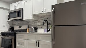 A modern kitchen with white cabinets, stainless steel appliances, and a tiled backsplash.