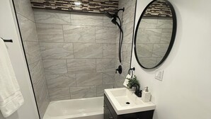 A bathroom with a bathtub, toilet, sink, and a mirror.
