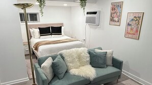 A modern bedroom with a bed, a sofa, a floor lamp, and a small table.