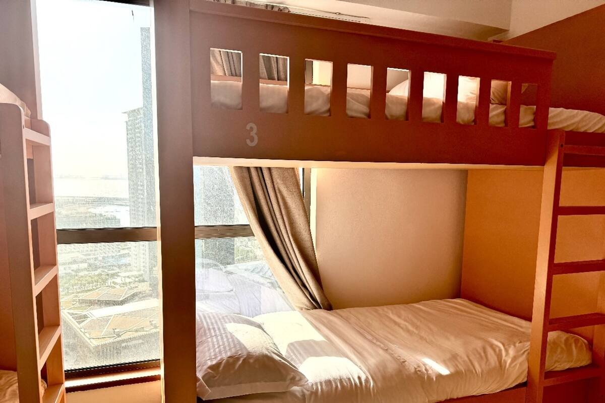 A bunk bed room with a city view, a window, and a wooden ladder.