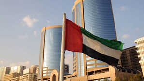 Un drapeau devant un bâtiment moderne à la façade incurvée et à l’extérieur vitré.
