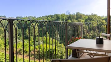 Un balcón con mesa y sillas, con vistas a un paisaje verde y exuberante.