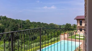 Ein Pool mit Blick auf eine bewaldete Landschaft und ein Gebäude im Hintergrund.