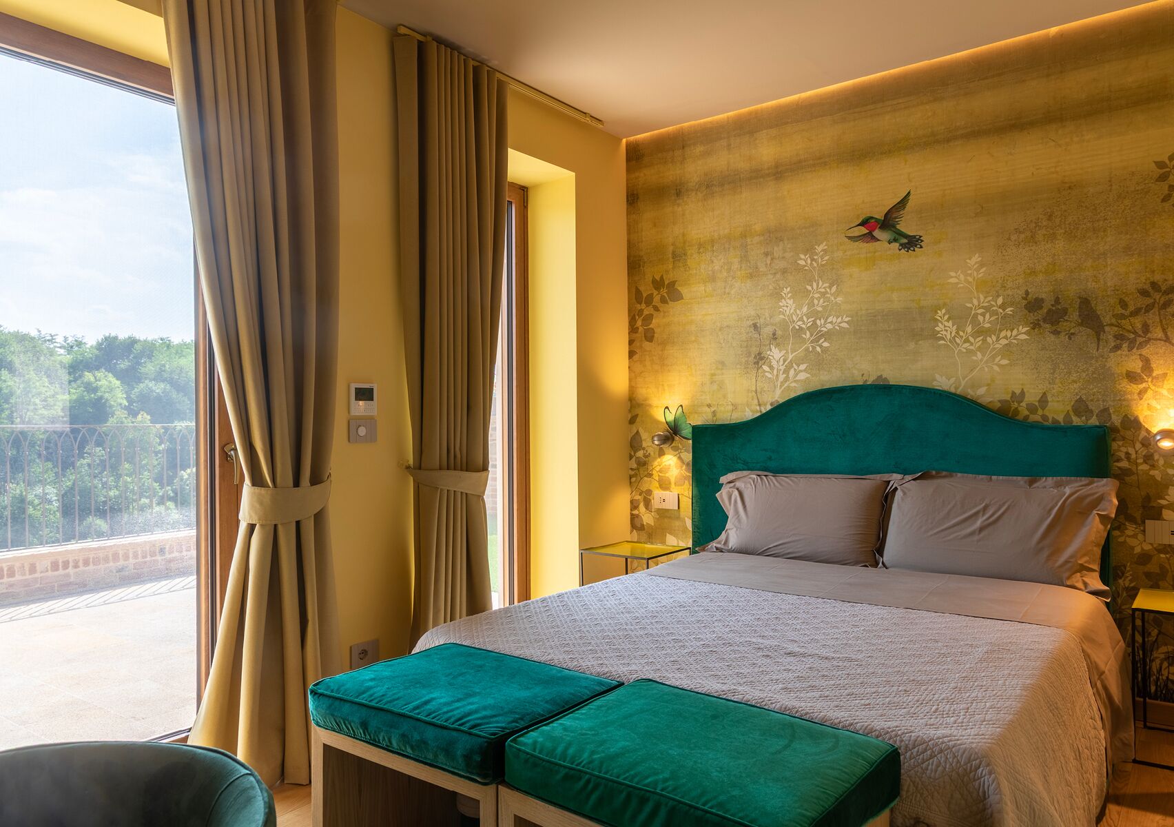 Une chambre d’hôtel avec un lit, une vue sur un pont et un mur orné d’une fresque représentant des oiseaux.
