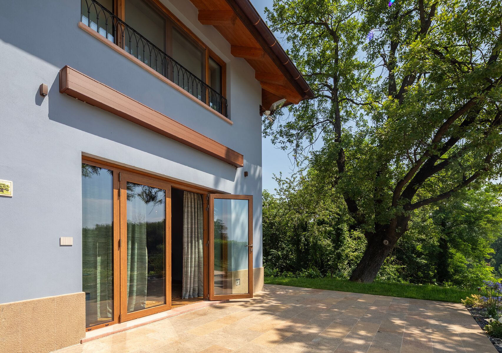A two-story house with large sliding glass doors and a balcony.