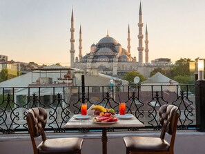 A balcony with a table set for two, overlooking a historic building with multiple minarets. - Grand Ambiance Hotel (Istanbul)