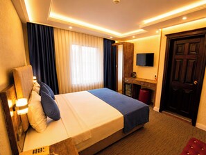 A hotel room with a bed, curtains, a television, a desk, and a door. - Grand Ambiance Hotel (Istanbul)