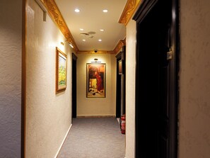 A hallway with a framed painting, a fire extinguisher, and a door with a number sign. - Grand Ambiance Hotel (Istanbul)