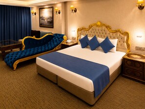 A hotel room with a large bed, a sofa, a nightstand, and a painting on the wall.