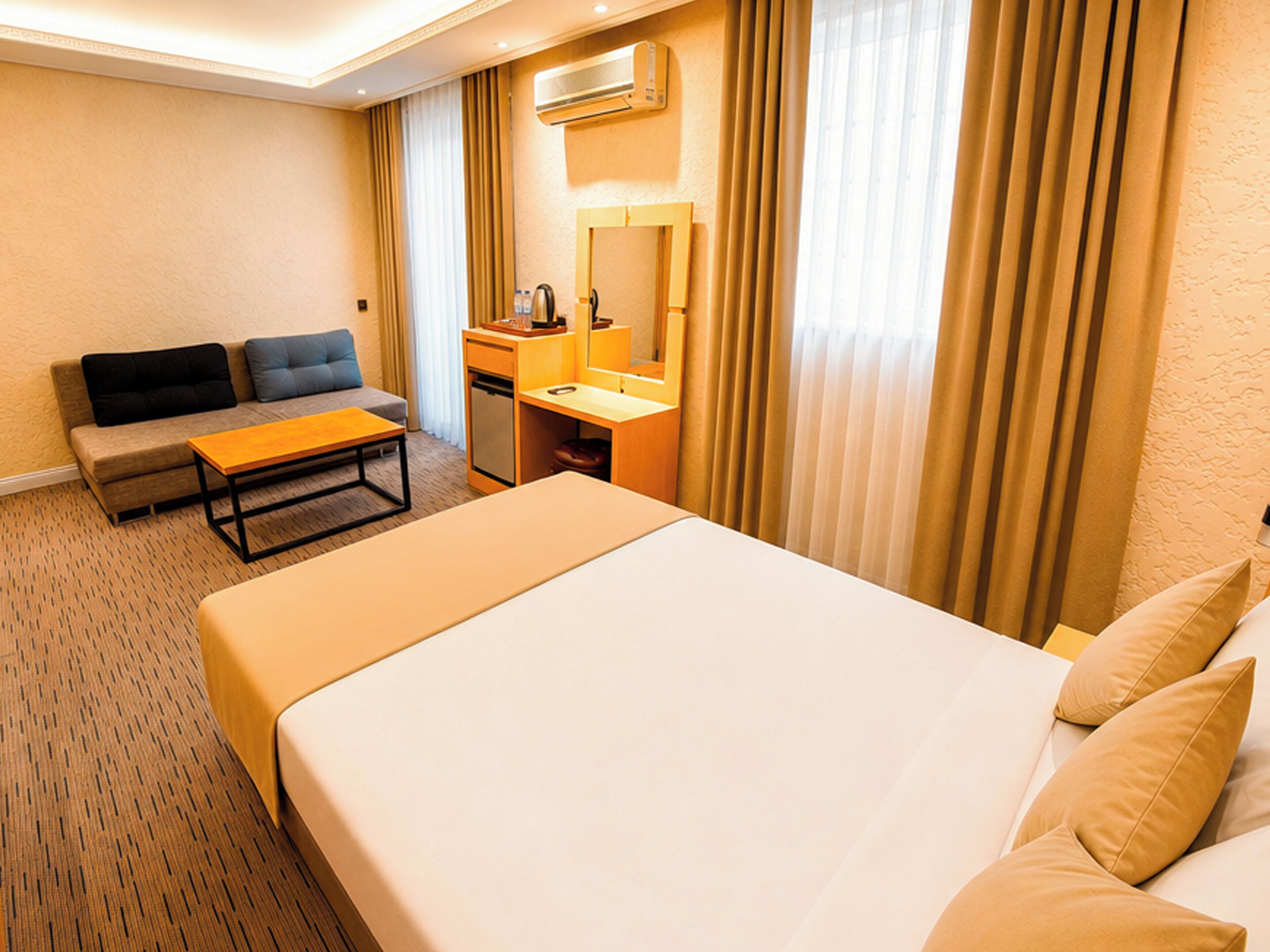 Una habitación de hotel con cama, sofá, escritorio y espejo.