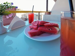 A table with a plate of watermelon slices, a glass of red beverage, and a vase with flowers. - Grand Ambiance Hotel (Istanbul)