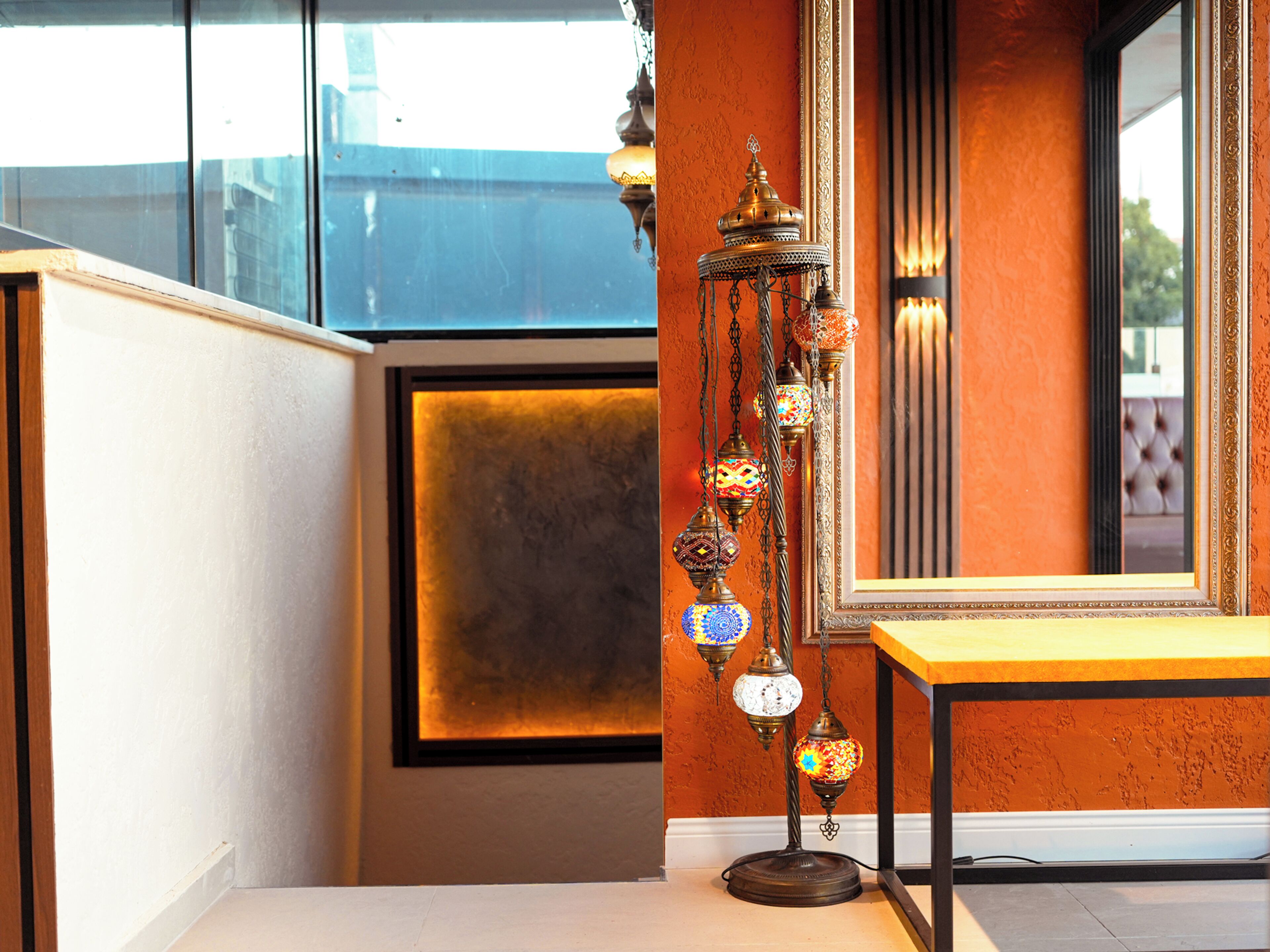 A room with a large mirror, a decorative hanging lamp, and a wooden table.